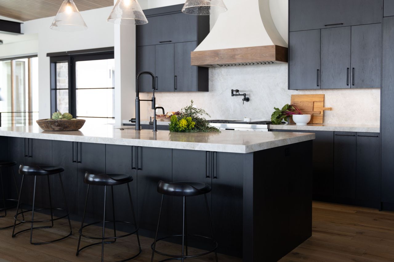 Kitchen with charcoal oak cabinets, a plaster range hood with walnut band and a quartzite island