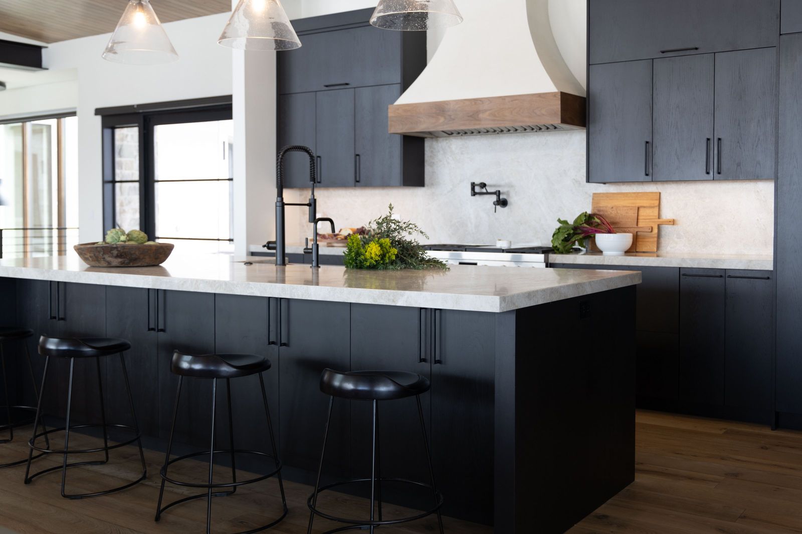 Kitchen with charcoal oak cabinets, a plaster range hood with walnut band and a quartzite island