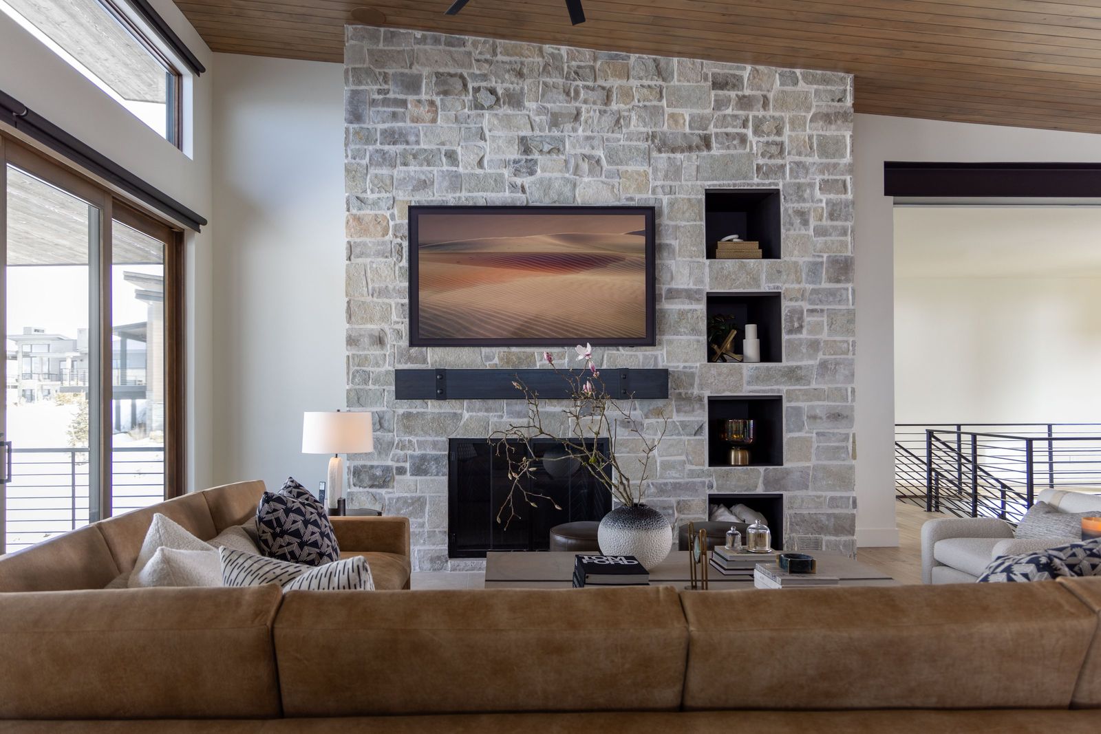 Stacked-stone fireplace wall with black niches above a cognac leather sectional