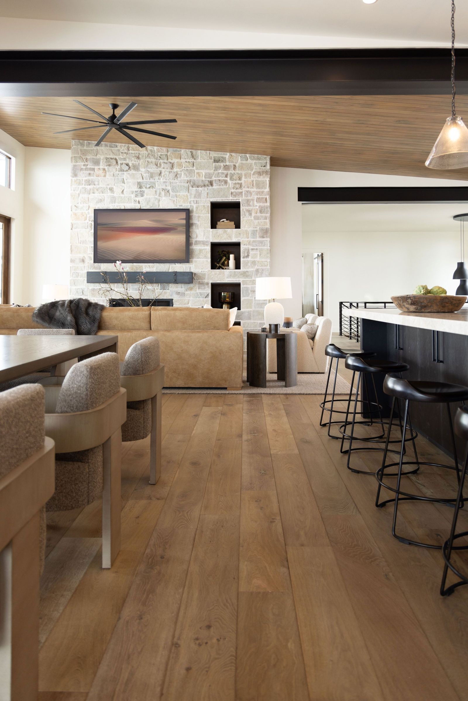 View past curved dining chairs and the kitchen island toward the living area and fireplace