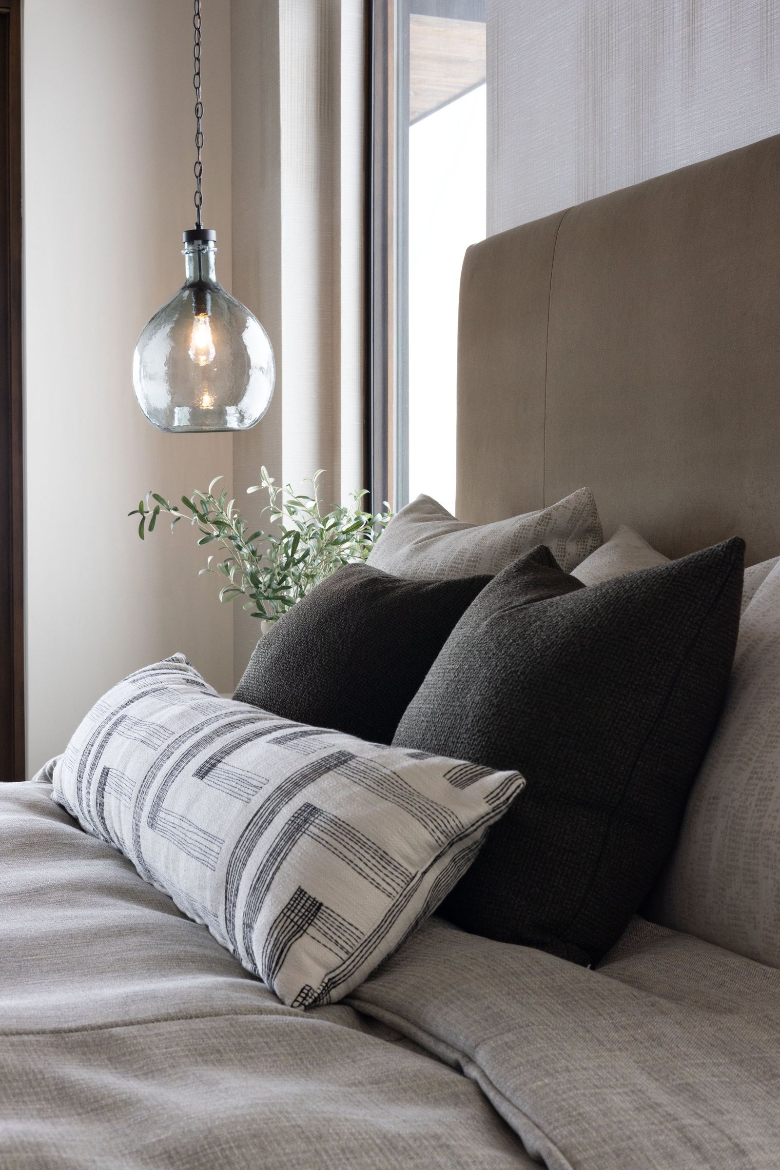 Charcoal and striped pillows layered against a bronze upholstered headboard