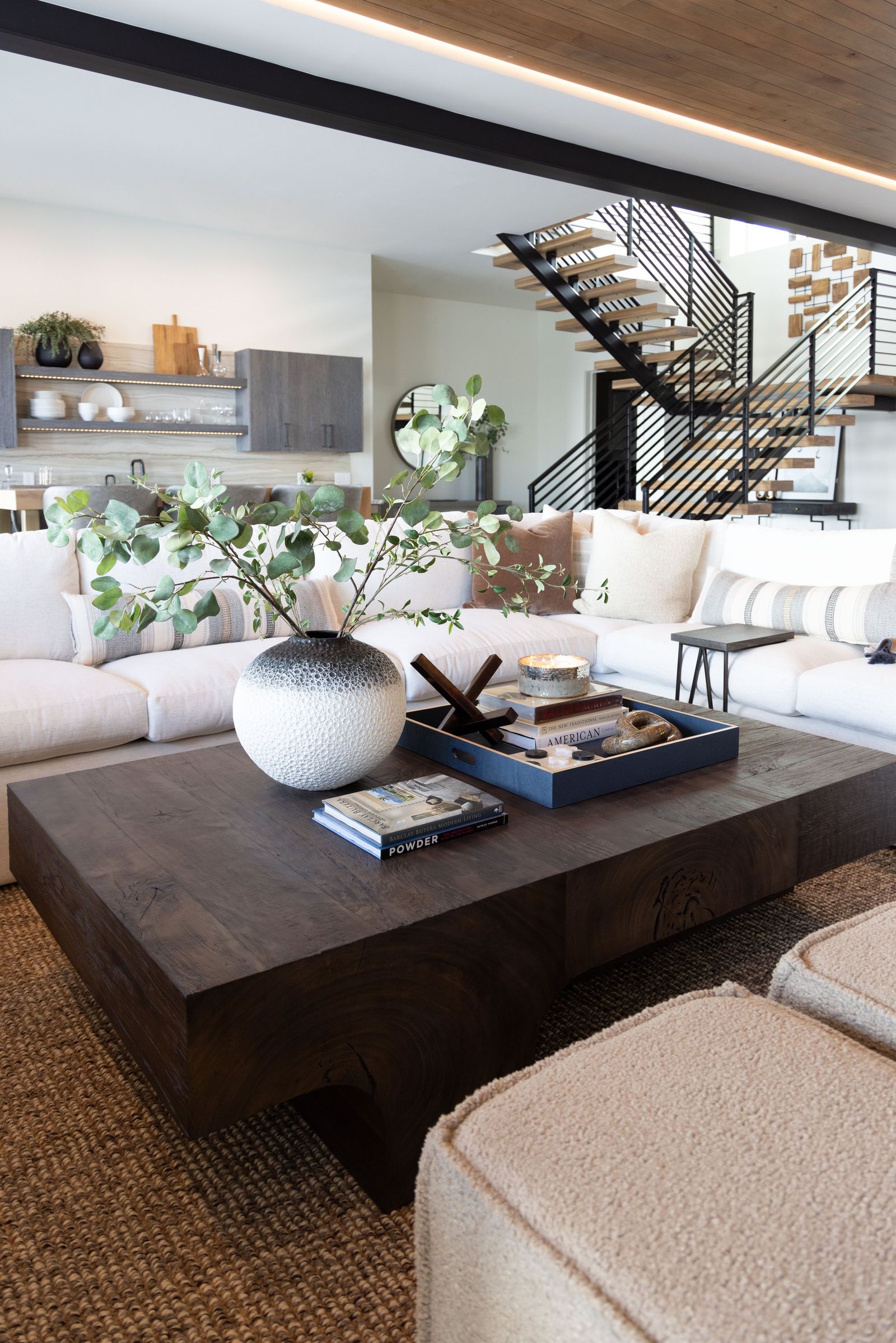 Chunky dark oak coffee table and boucle ottomans in a cream sectional seating group