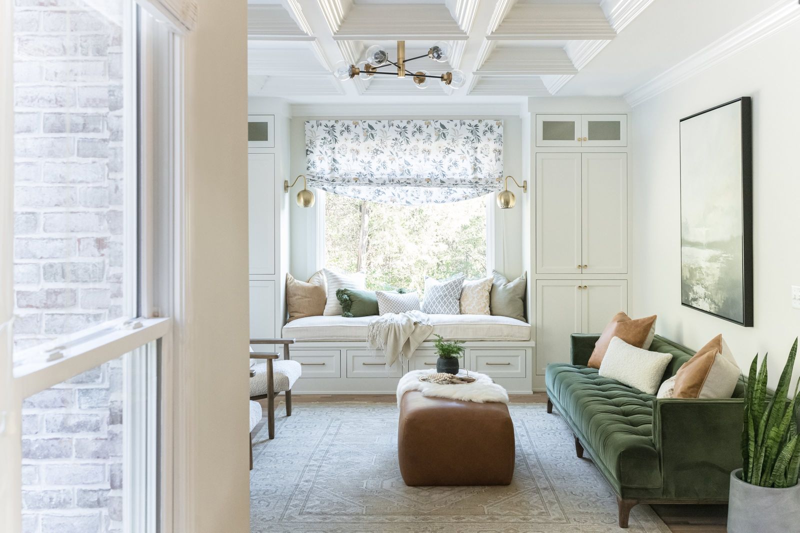 Morning room with a cushioned window seat, green velvet sofa and cognac leather ottoman