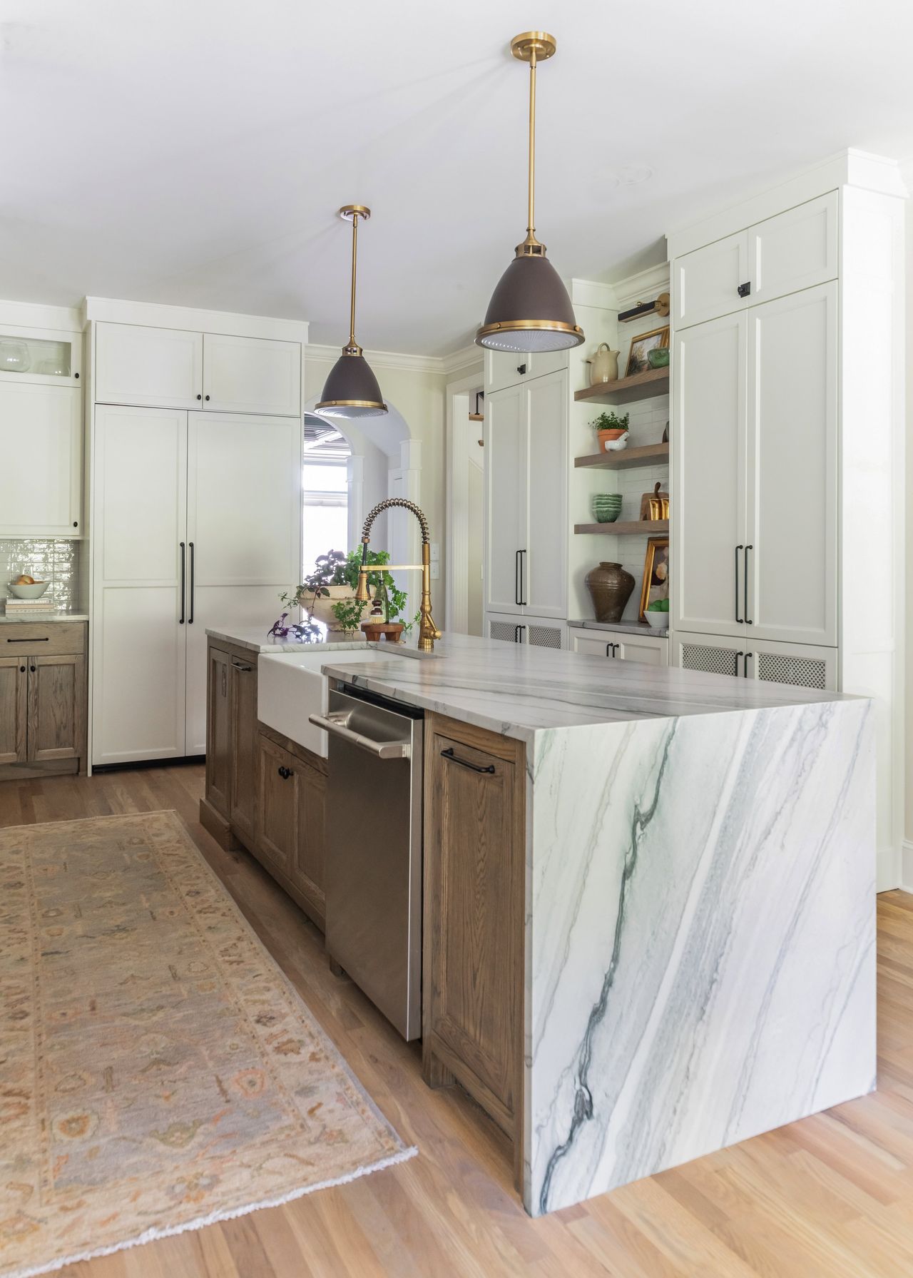 Long view down the finished waterfall island toward a tall paneled pantry wall