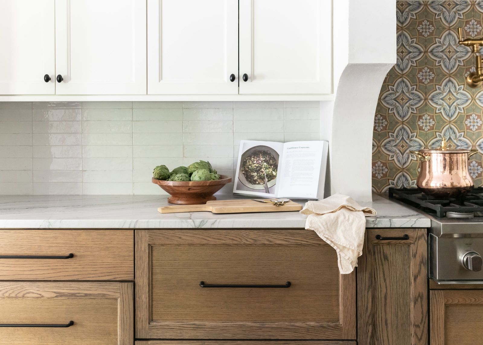 Oak drawers, marble counter and a copper pot beside the patterned tile range alcove