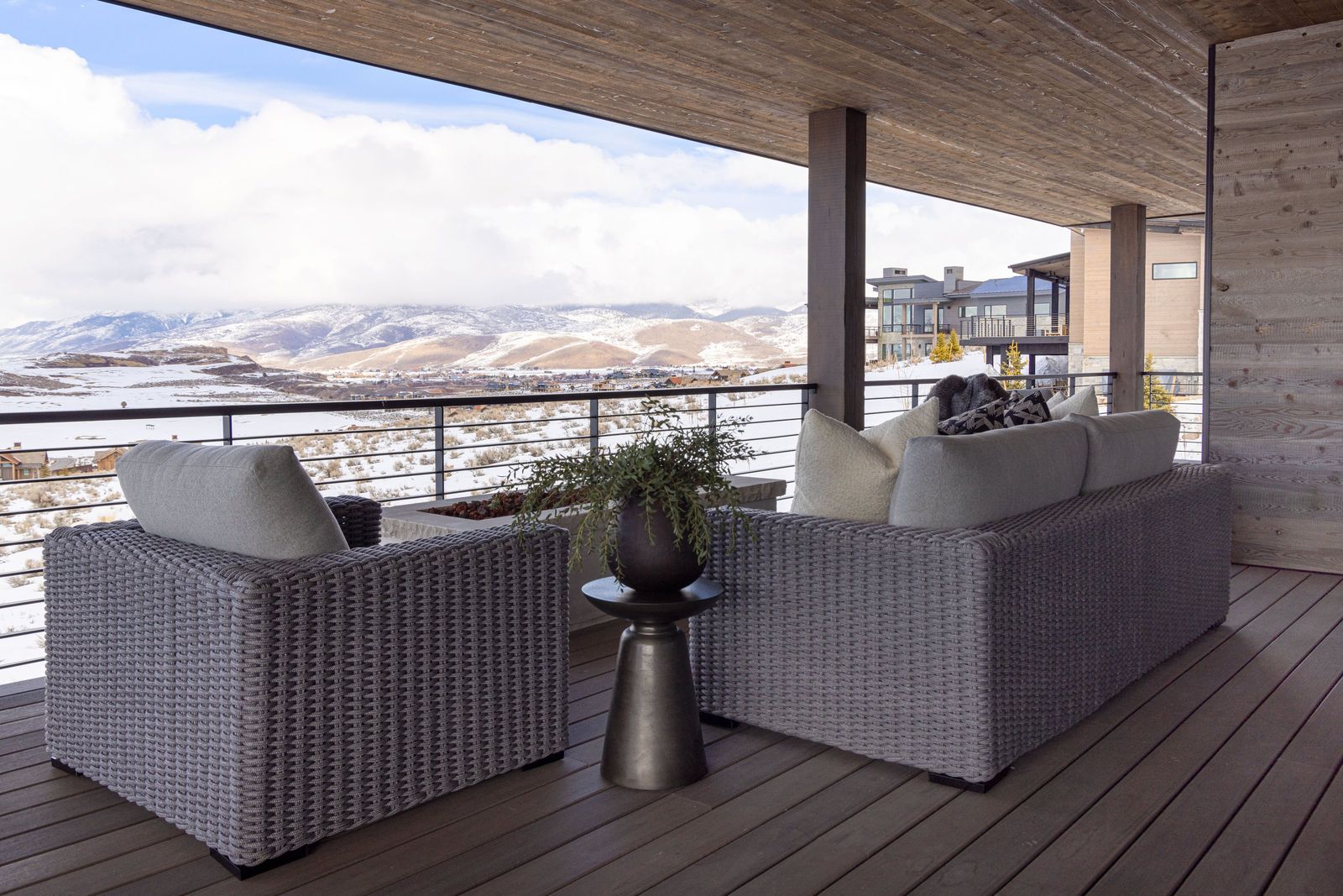 Covered patio with woven lounge chairs overlooking snow-dusted Wasatch Back hills