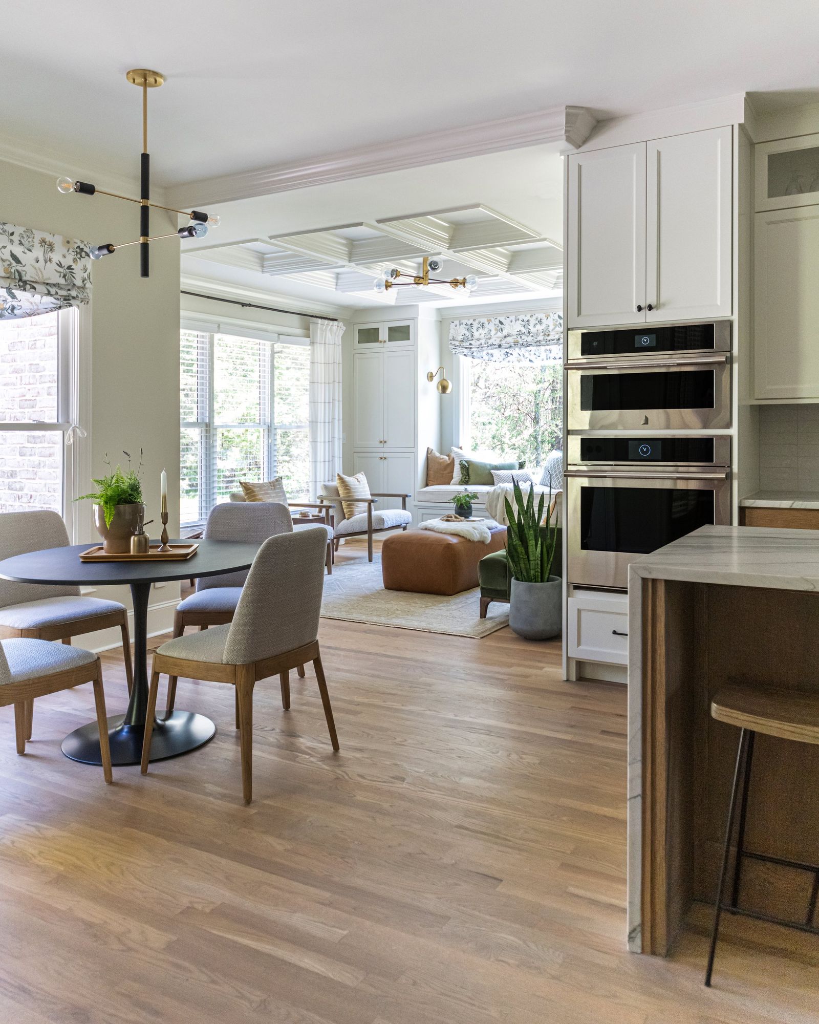 From the kitchen toward a round breakfast table and the coffered morning room beyond