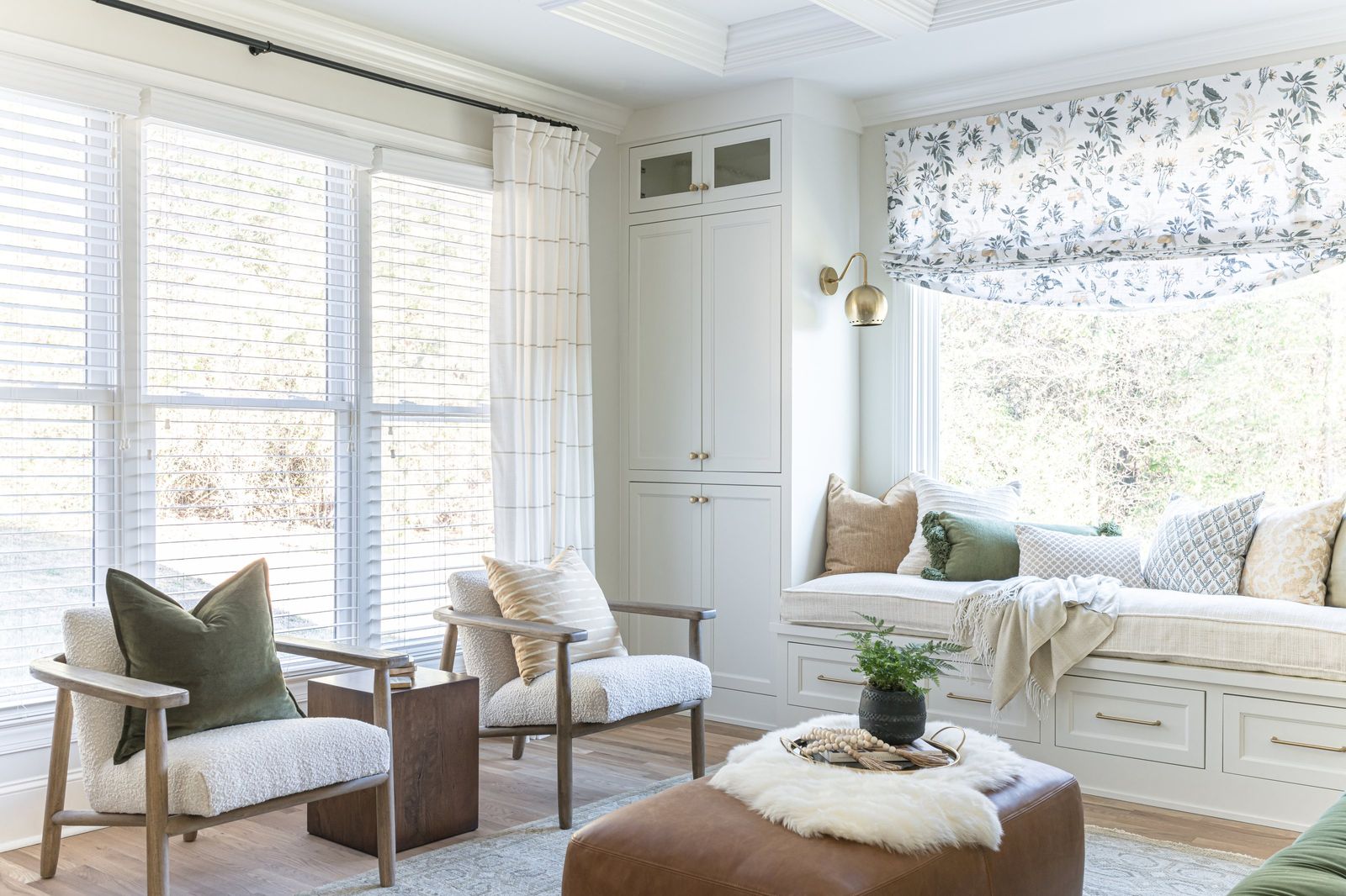 Sunlit corner with oak lounge chairs, a floral Roman shade and the window seat