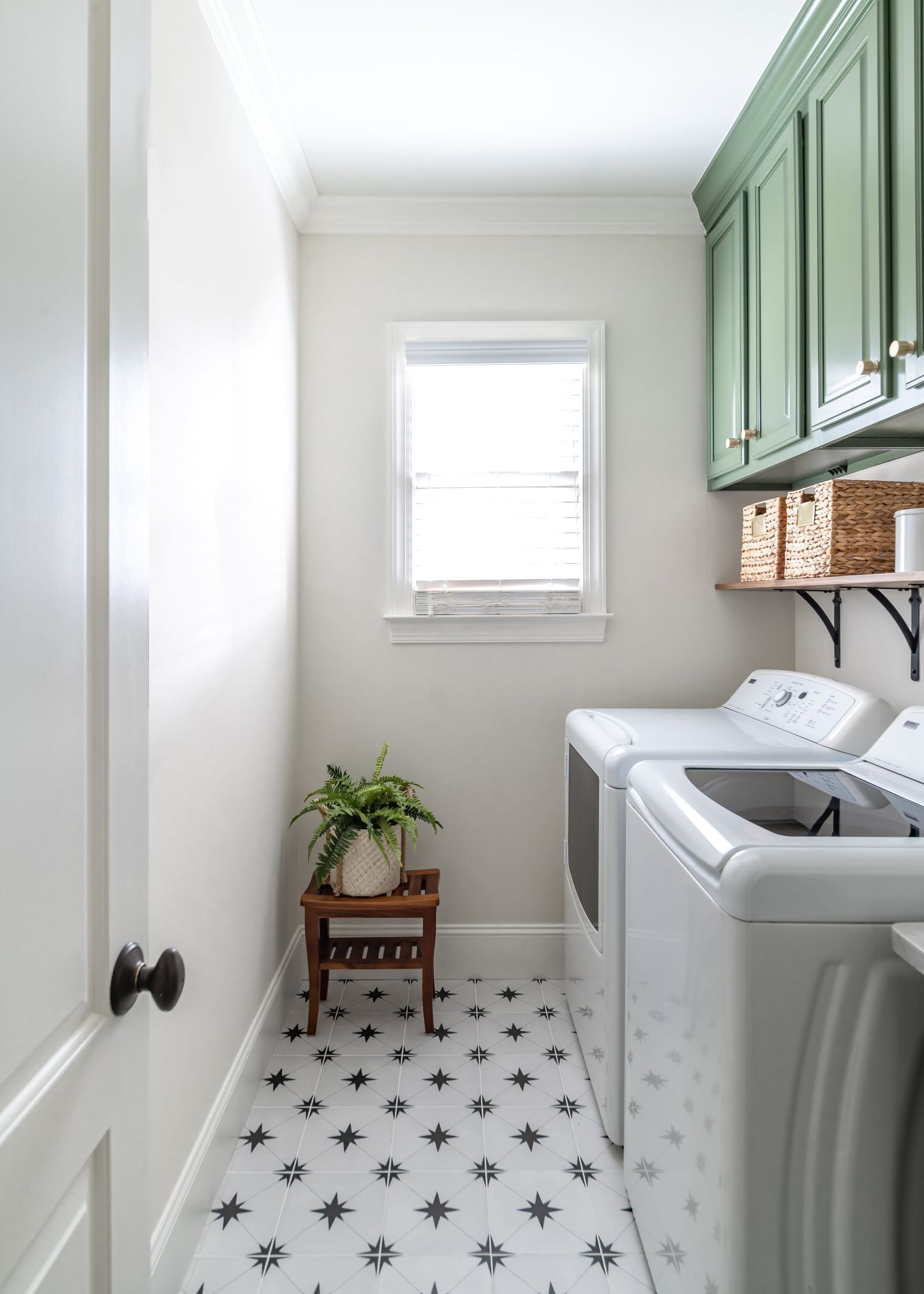 Laundry room with green cabinetry and star-pattern floor tile seen through the doorway