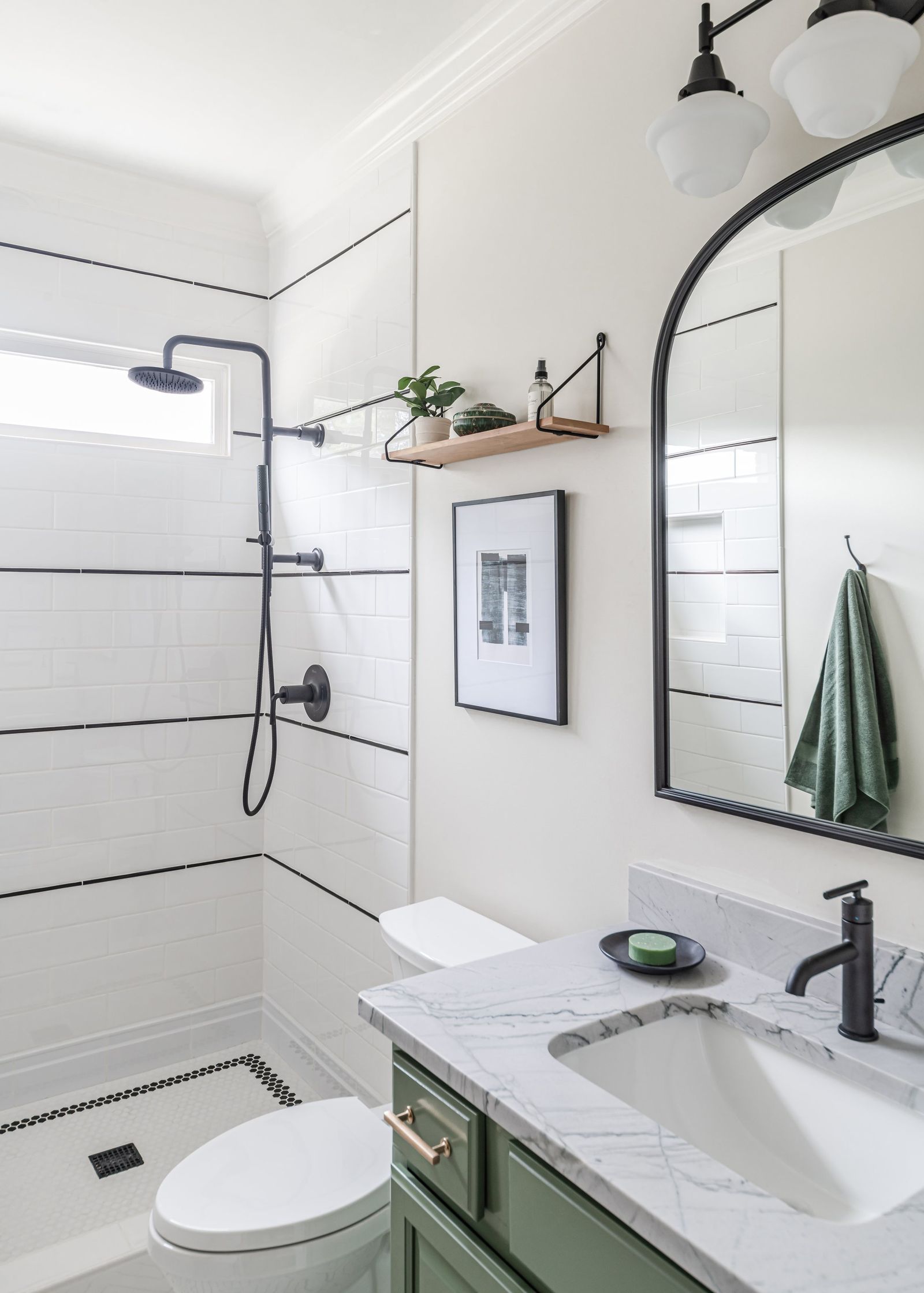 Guest bath with pinstripe tile shower, arched black mirror and green vanity