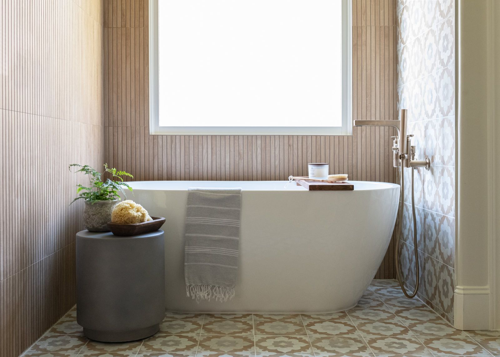 Freestanding tub against fluted wood-look tile with a patterned tile accent wall