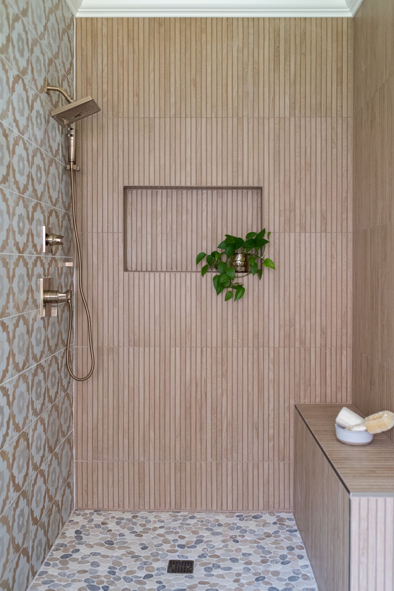 Walk-in shower with fluted tile, brass fixtures and a recessed niche