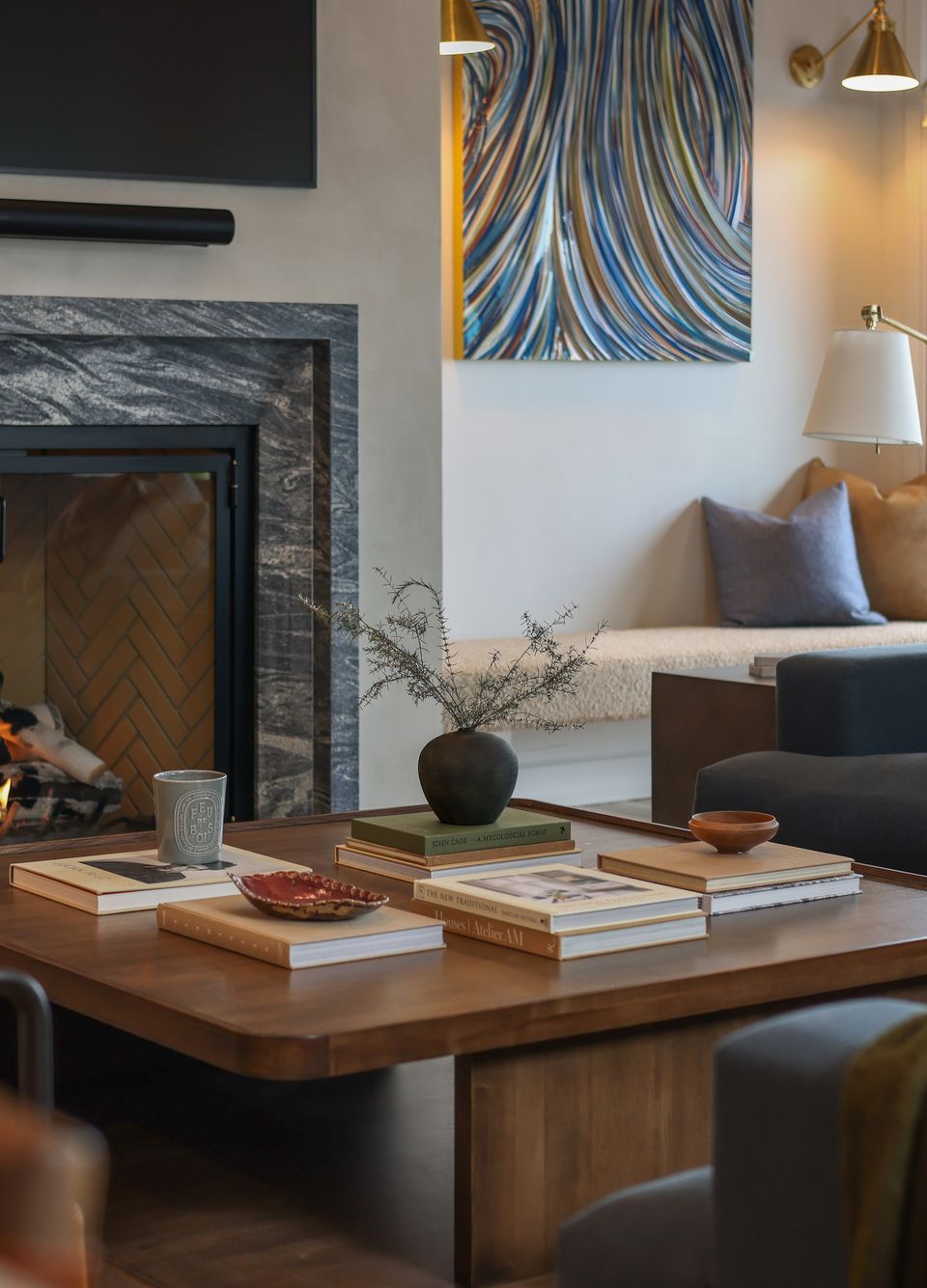 Marble fireplace, abstract art and a walnut coffee table stacked with books