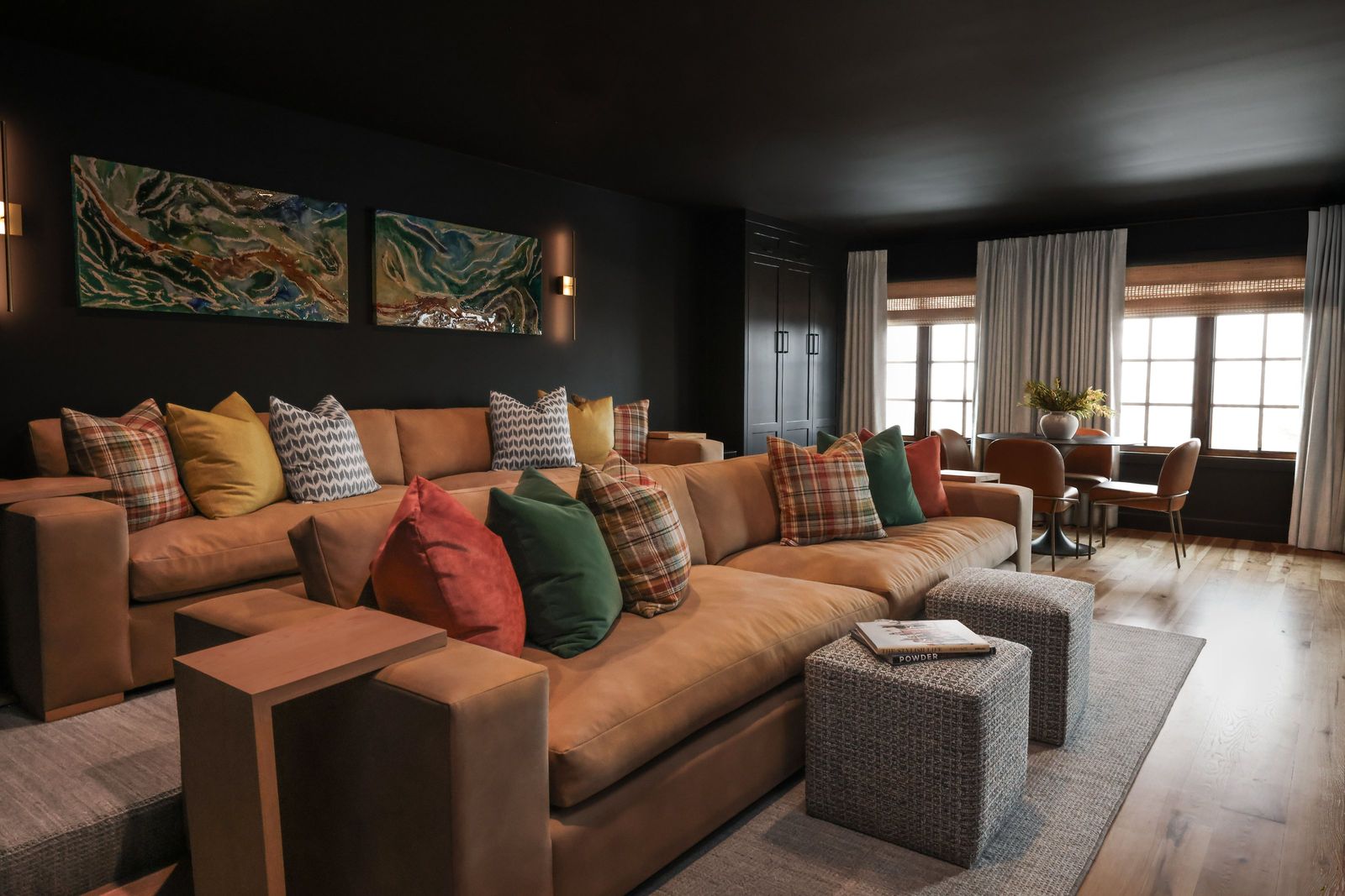 Moody entertainment room with a cognac sectional, plaid and jewel-tone pillows and dark walls