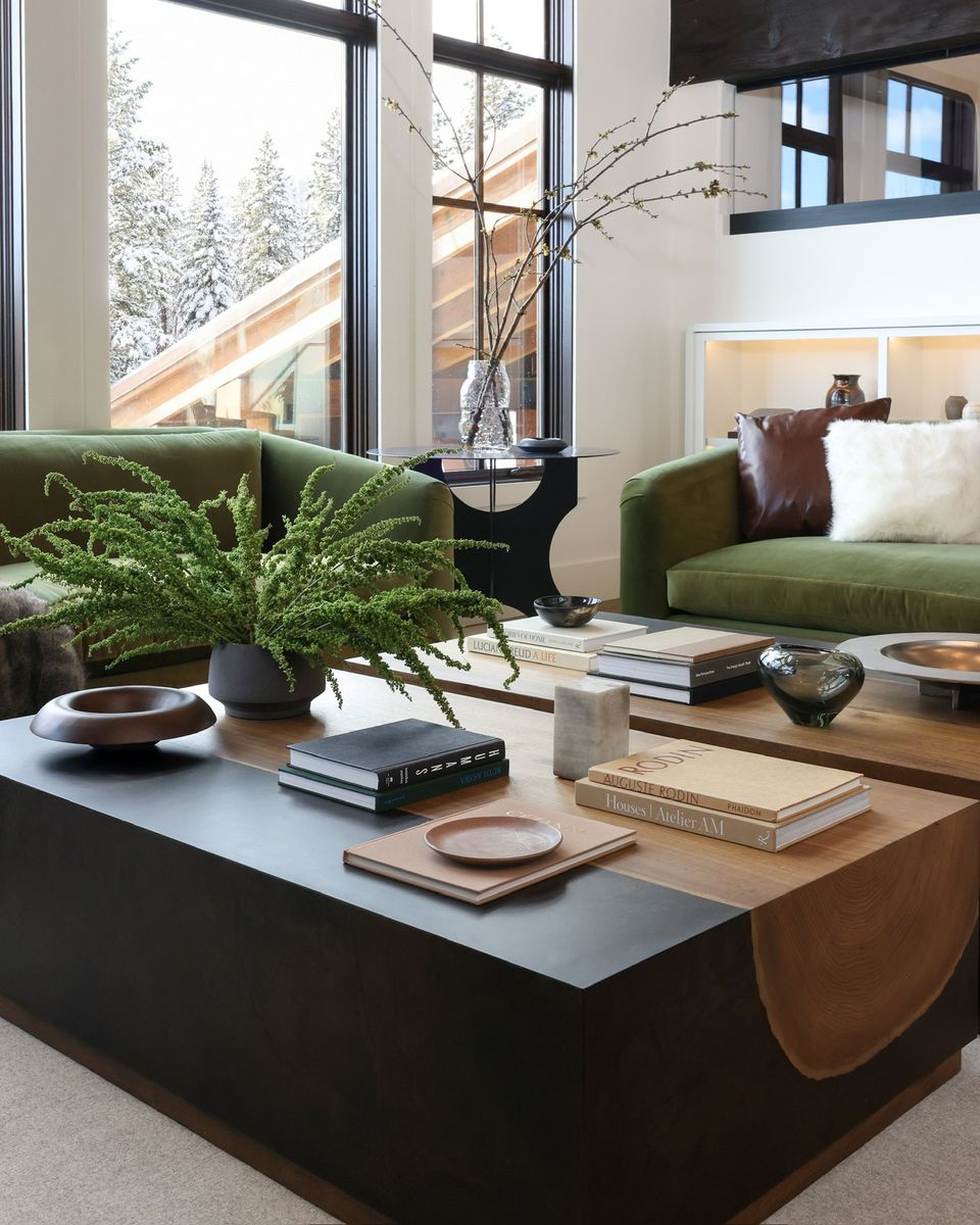 Black and oak coffee table styled with books, a fern and turned wood bowls