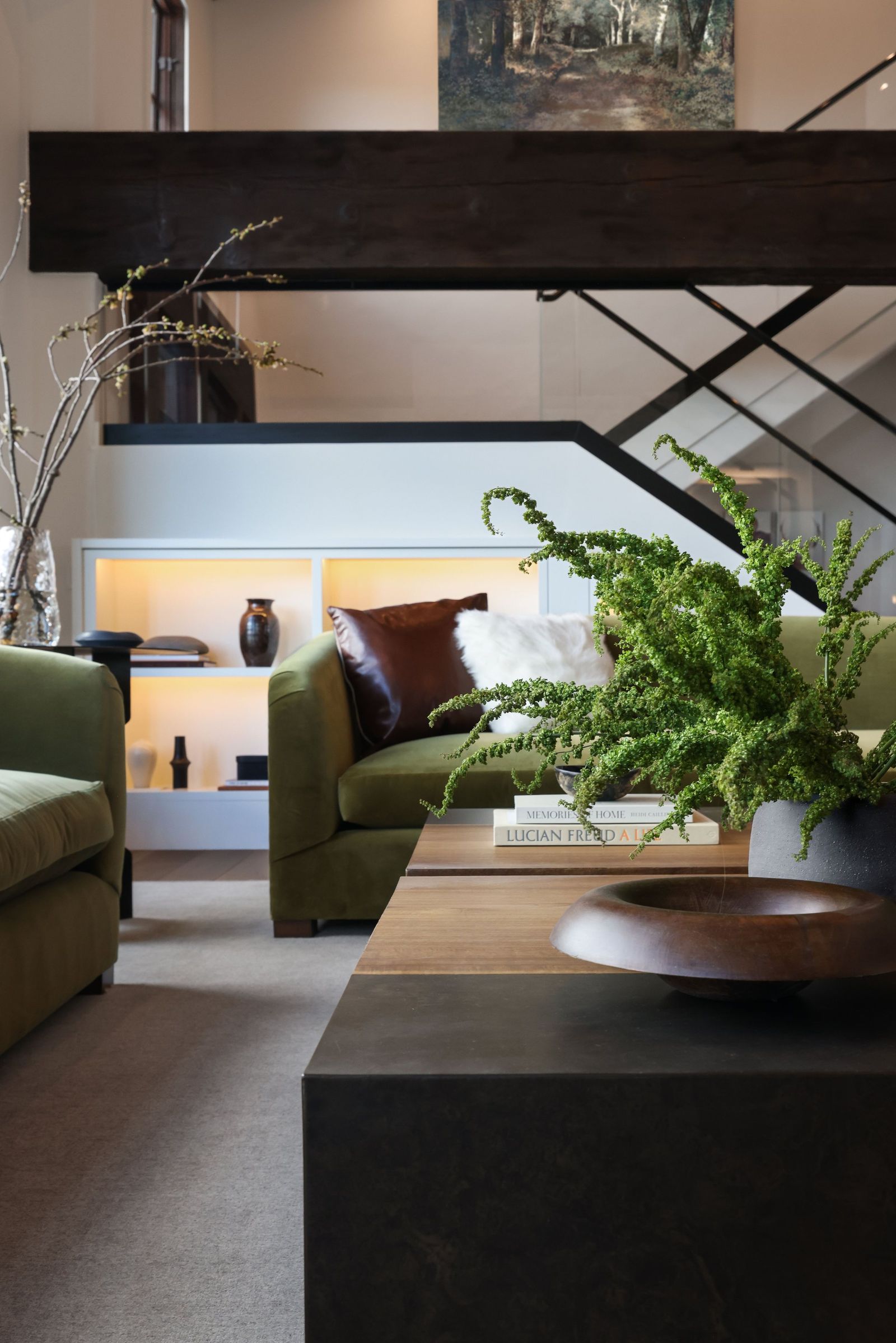 Olive sofa with leather and shearling pillows beneath a heavy timber beam