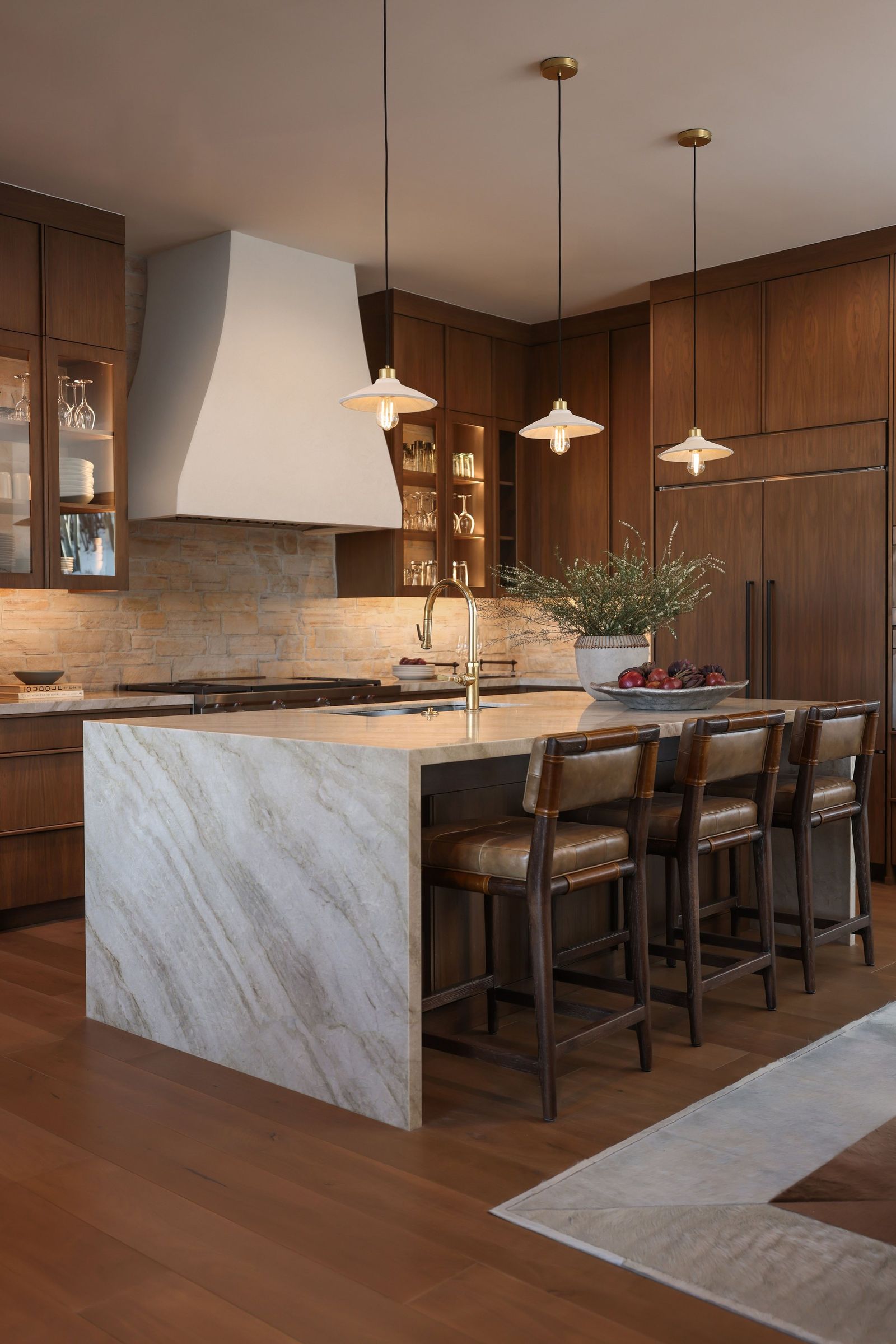 Walnut kitchen with a plaster hood, quartzite waterfall island and leather counter stools