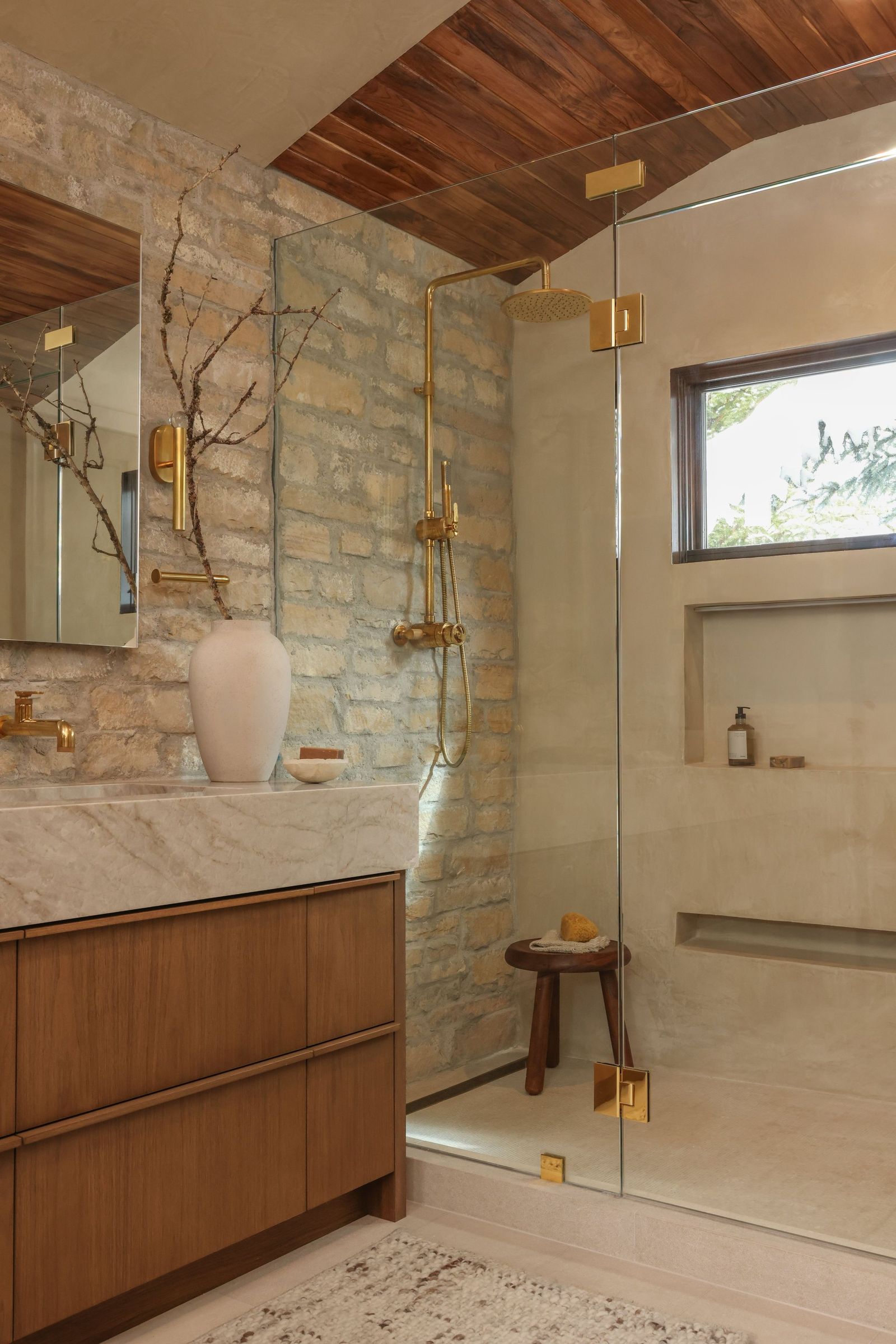 Glass steam shower with stacked stone, a brass rain head and a wood-plank ceiling