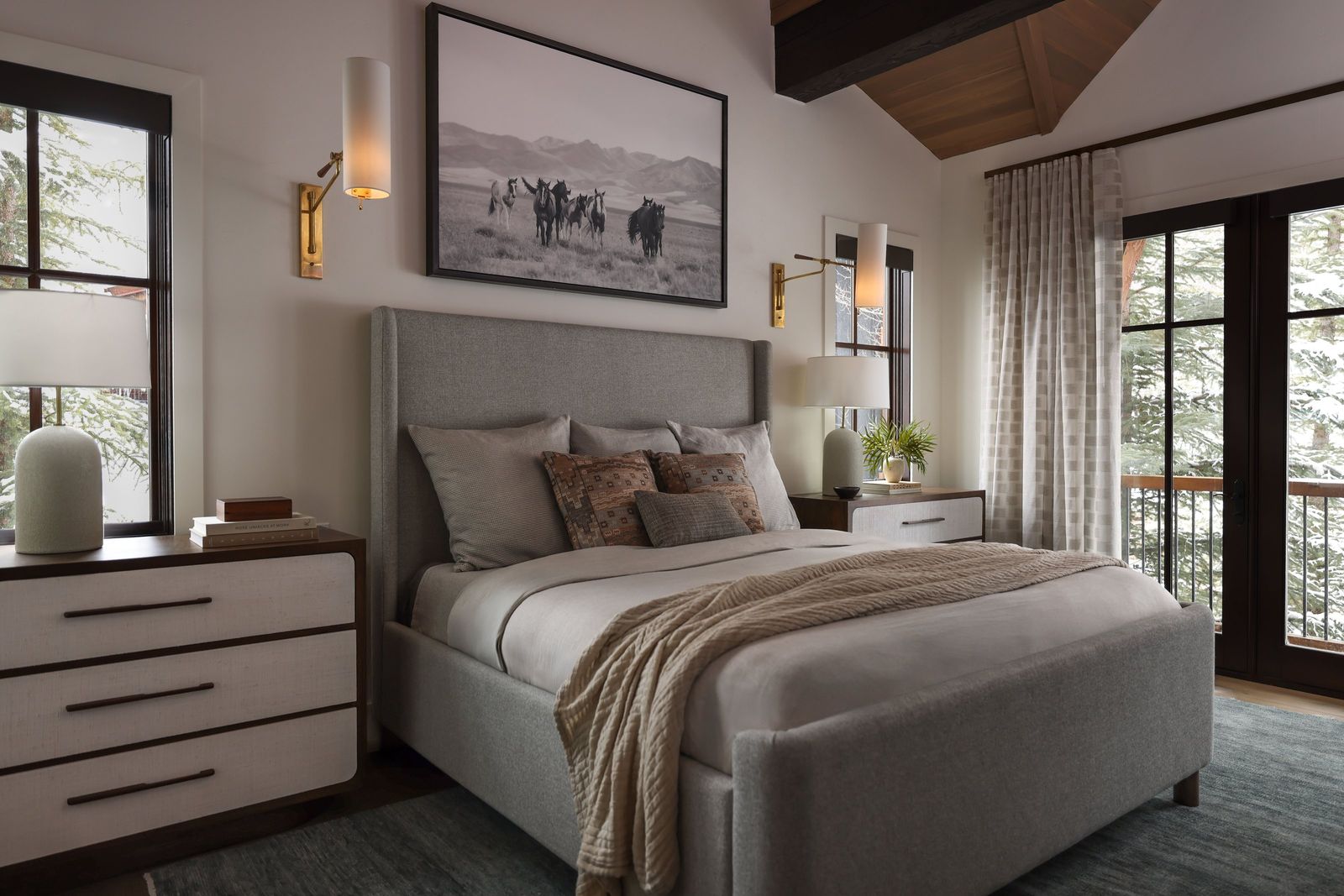 Primary bedroom with a grey upholstered bed, black-and-white horse photograph and brass sconces