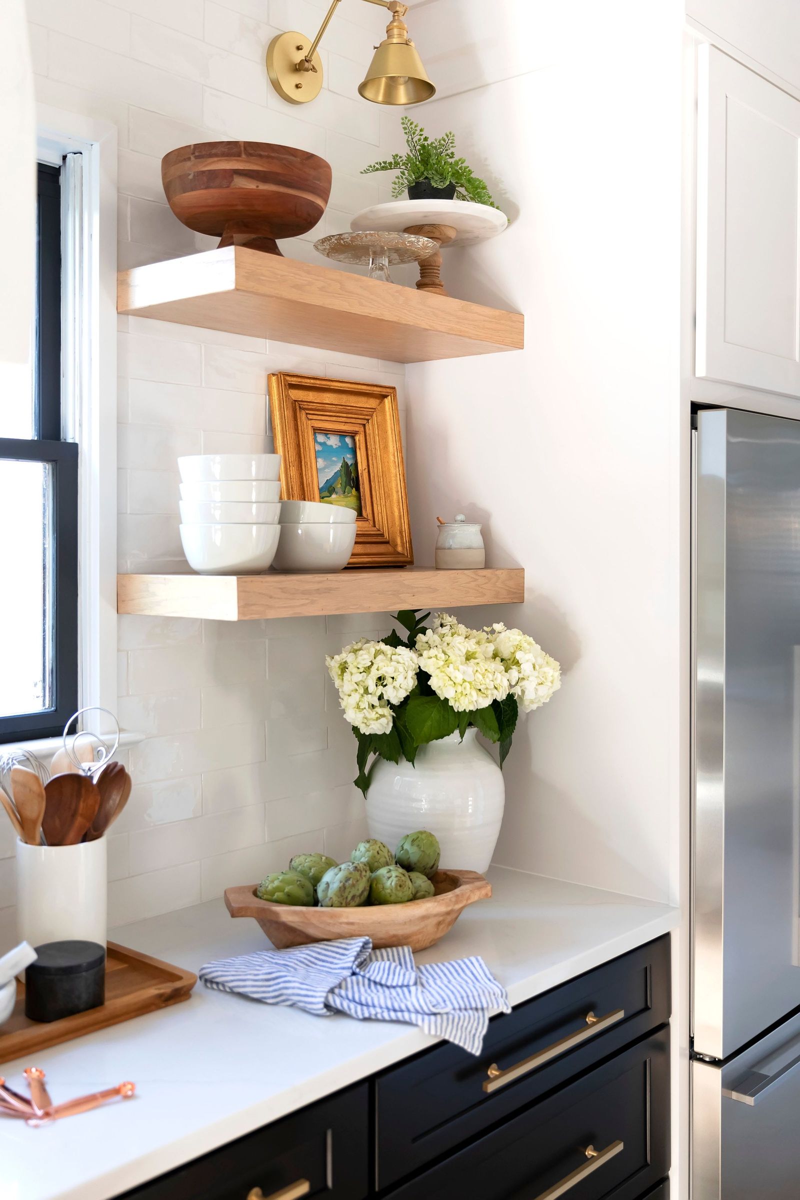 Floating shelves with a wooden bowl, hydrangeas and a gilt-framed landscape