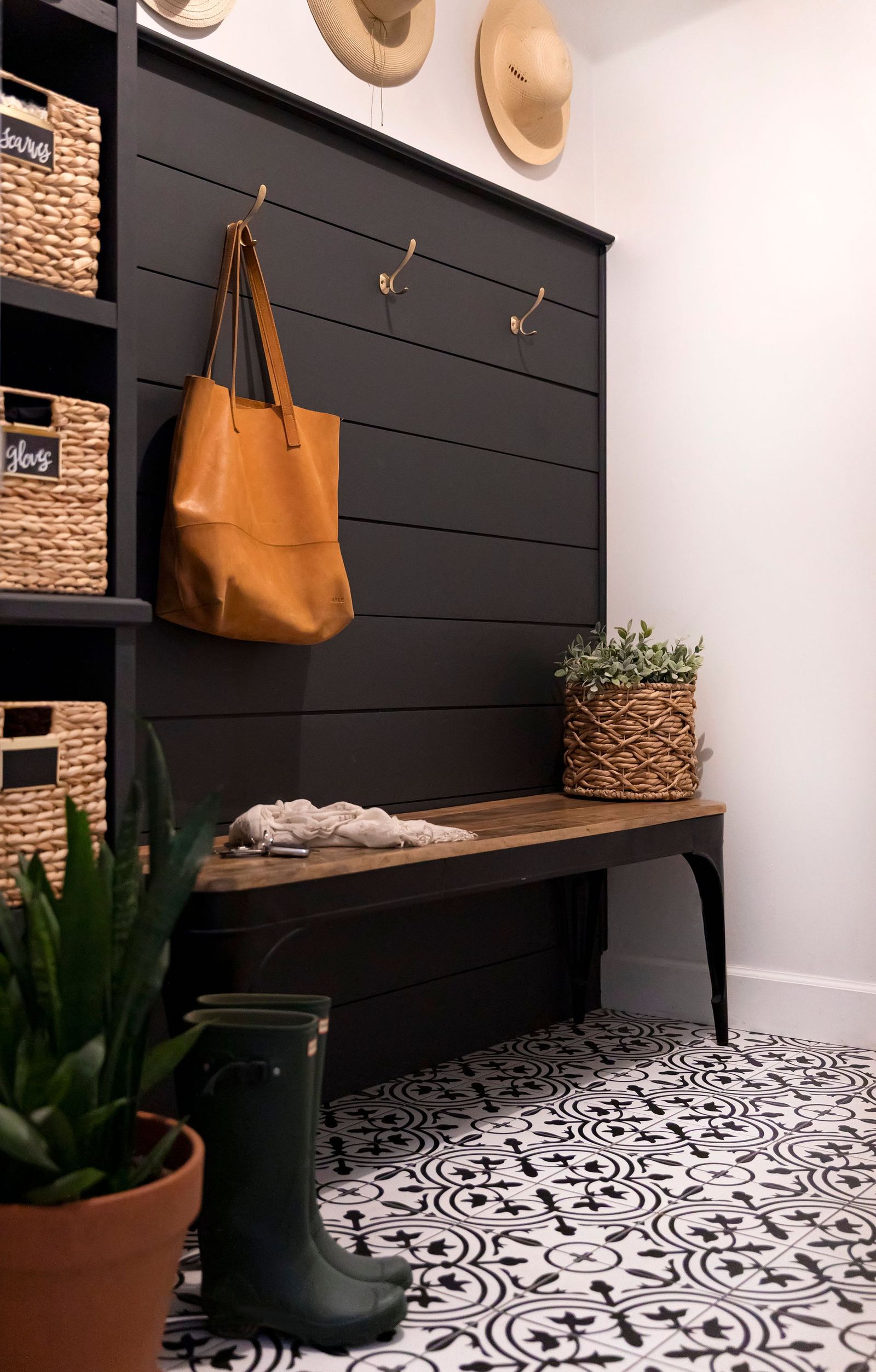 Mudroom with black shiplap, woven baskets, hat wall and a patterned cement tile floor
