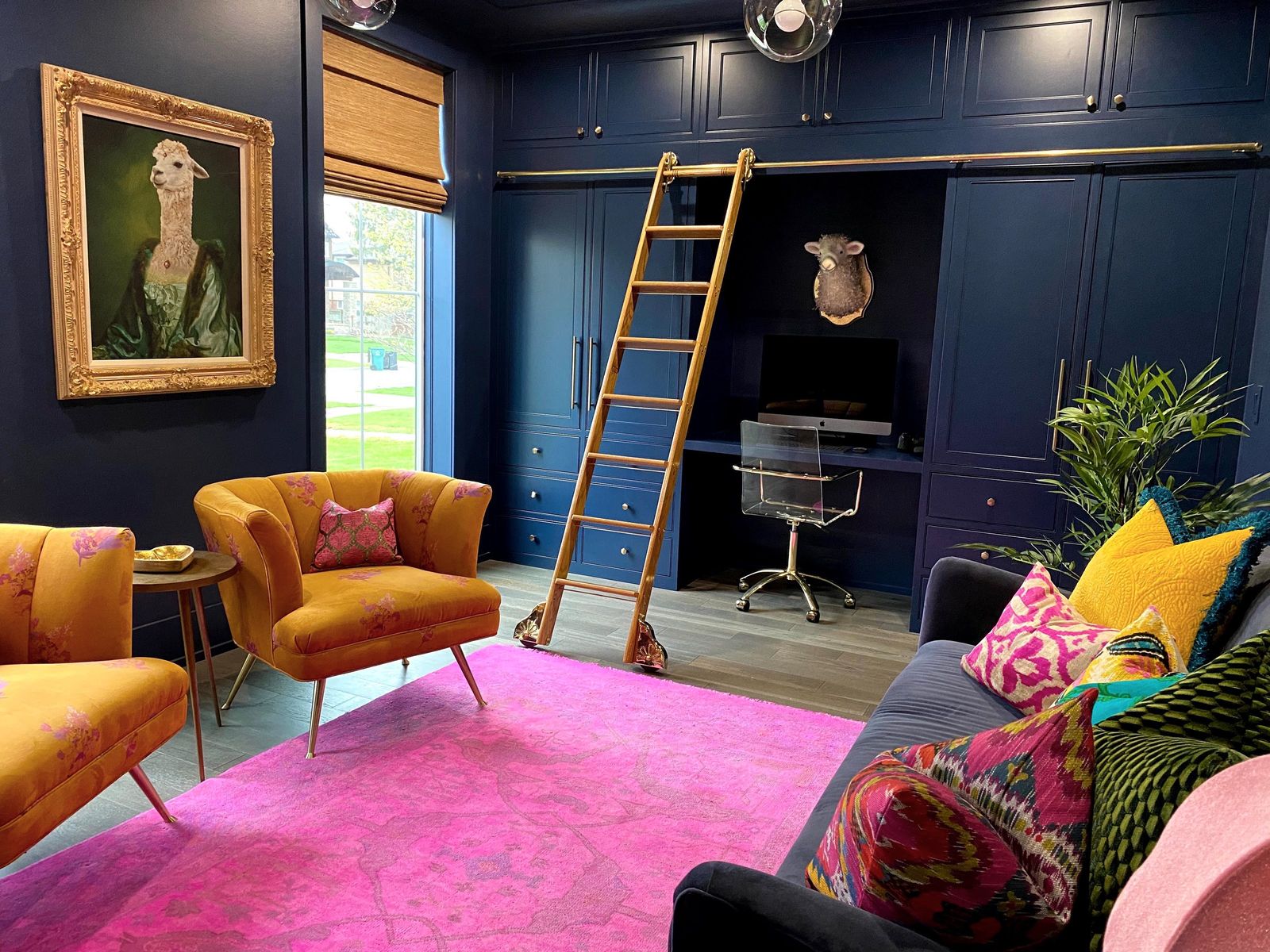 Navy library office with a brass ladder, mustard velvet chairs and a hot pink rug