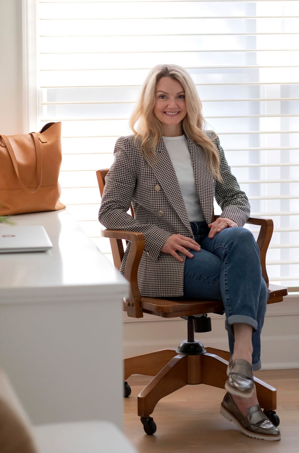 Joni Glass seated in her studio in a tweed blazer and jeans